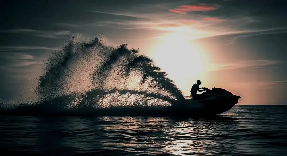Personal watercraft carving across open water at sunset